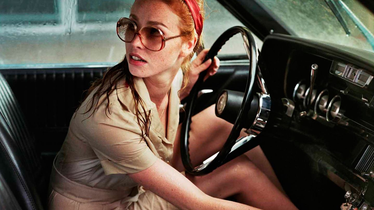 La dame dans l'auto avec des lunettes et un fusil