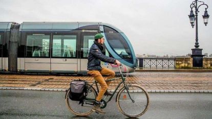 homme qui fait du vélo à côté d'un tramway