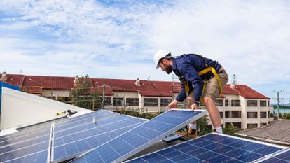 homme installant des panneaux solaires sur les toits